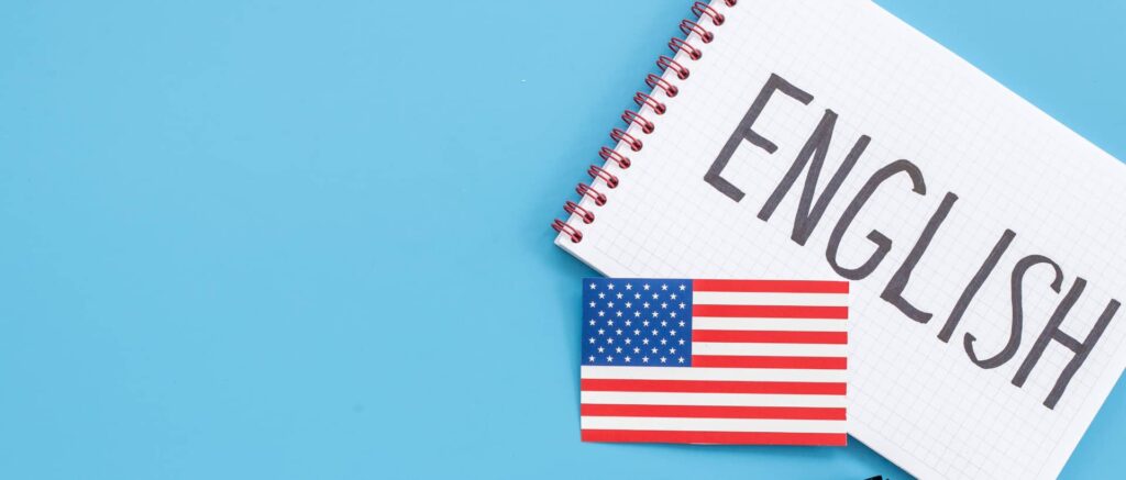 Una libreta abierta con la palabra "ENGLISH" escrita en mayúsculas con la bandera de los Estados Unidos al lado, todo sobre un fondo azul claro.